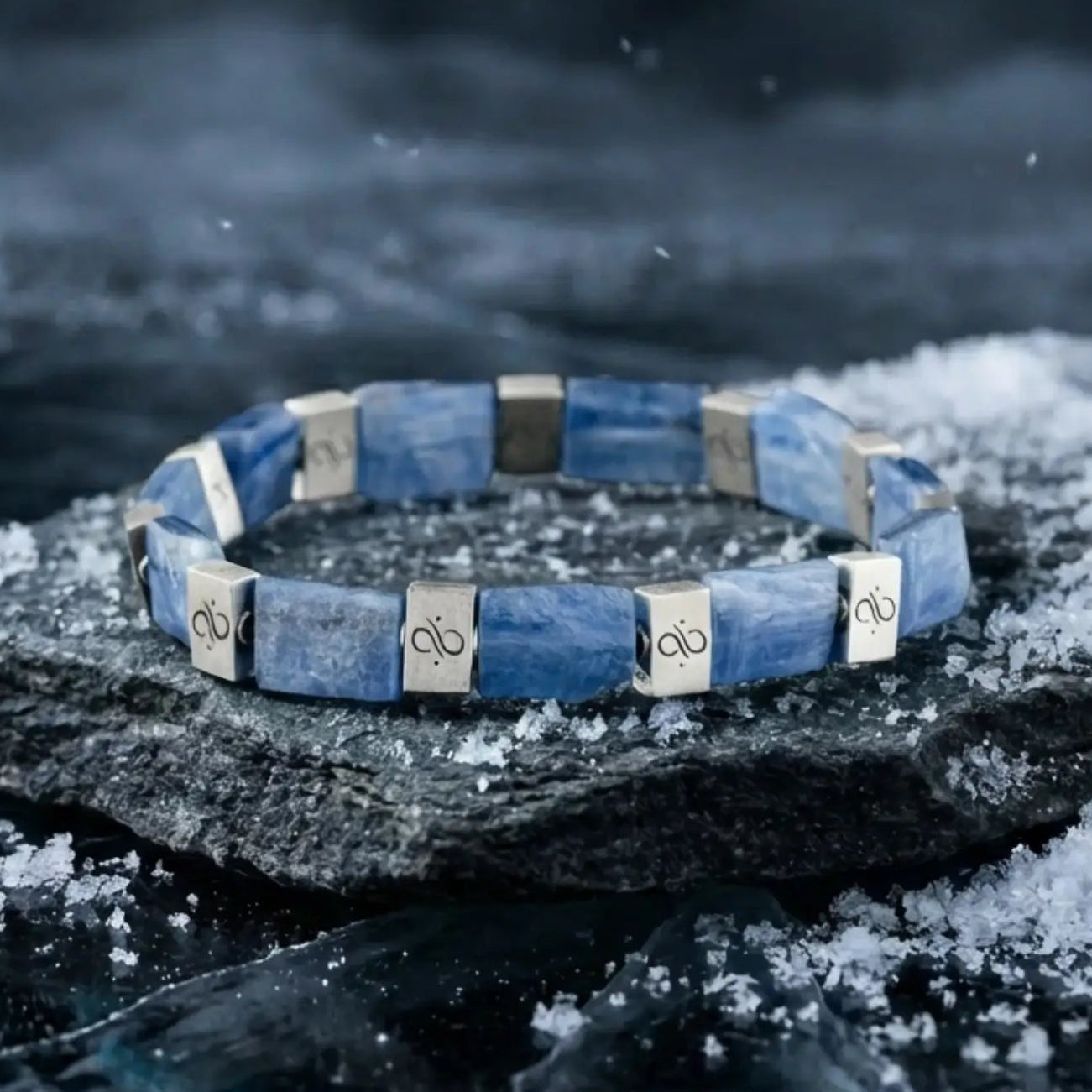 Blue bracelet with silver accents on a dark, snowy background
