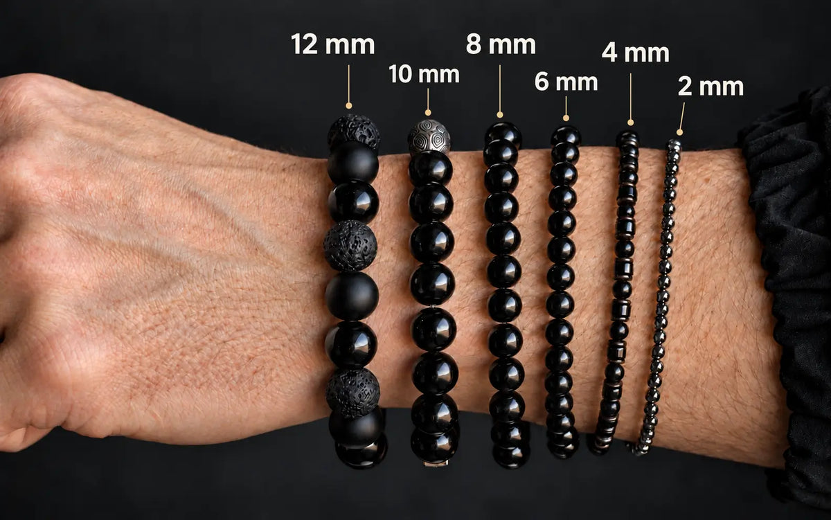 Six black bracelets on the same wrist comparing 12 mm, 10 mm, 8 mm, 6 mm, 4 mm and 2 mm bead sizes