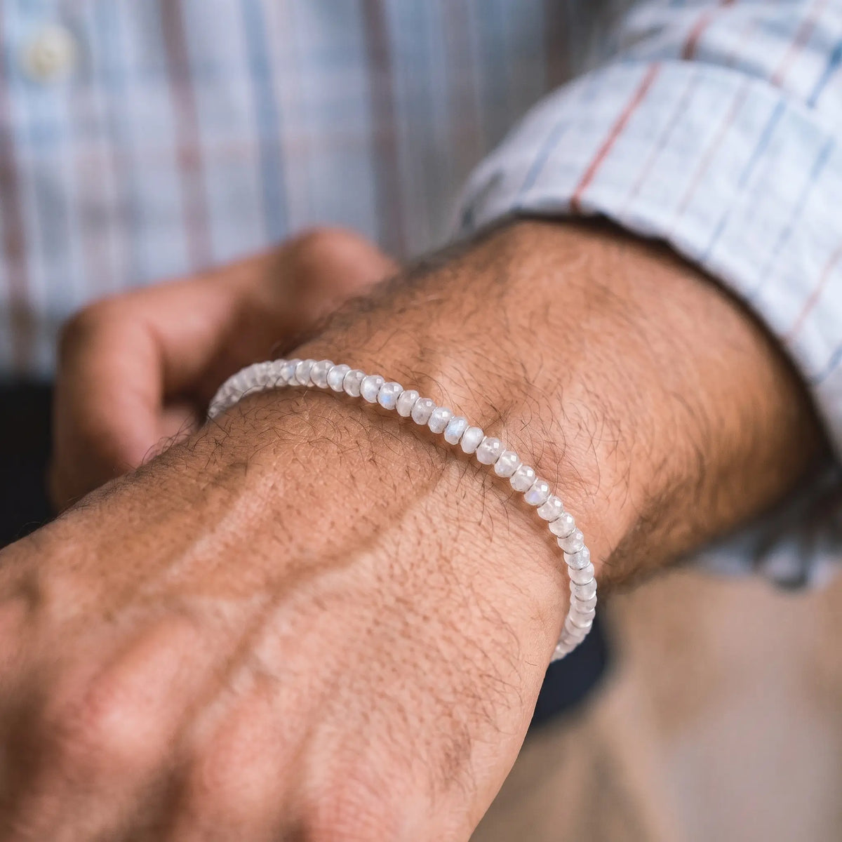 Moonstone Bracelet X (4mm), with pale faceted moonstone beads, worn alone beside a striped shirt cuff.
