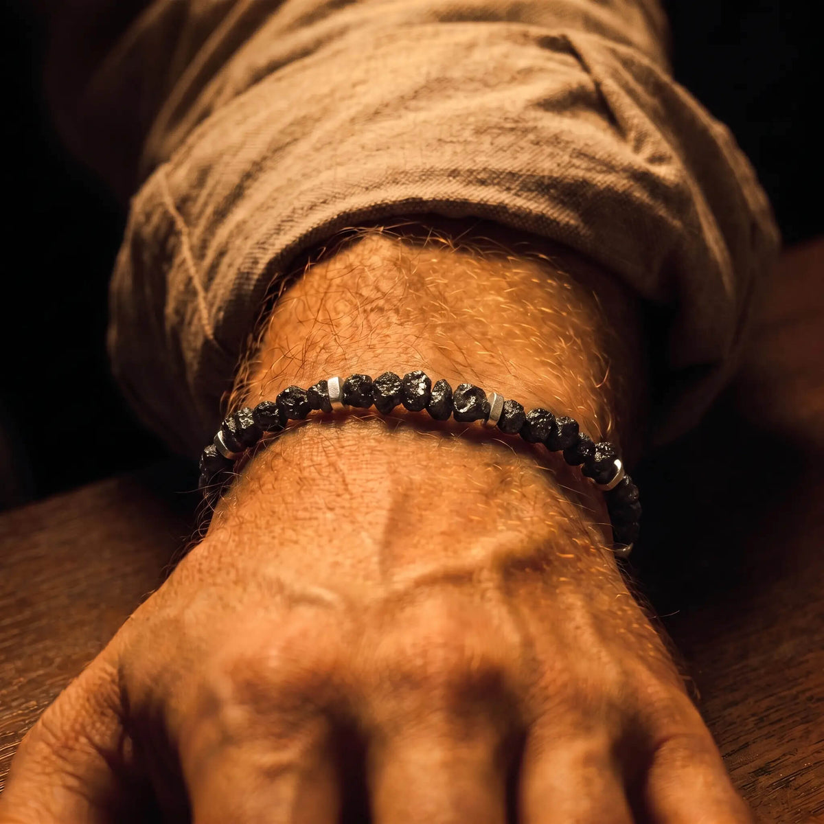 Raw Black Diamond — Bracelet on the wrist below a tan sleeve