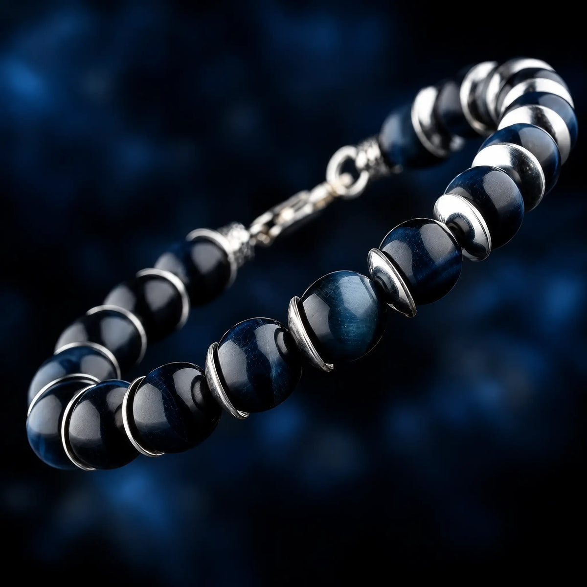 Blue Tiger Eye Bracelet V (10mm) by Aurum Brothers, angled view with silver spacers against a dark blue background.